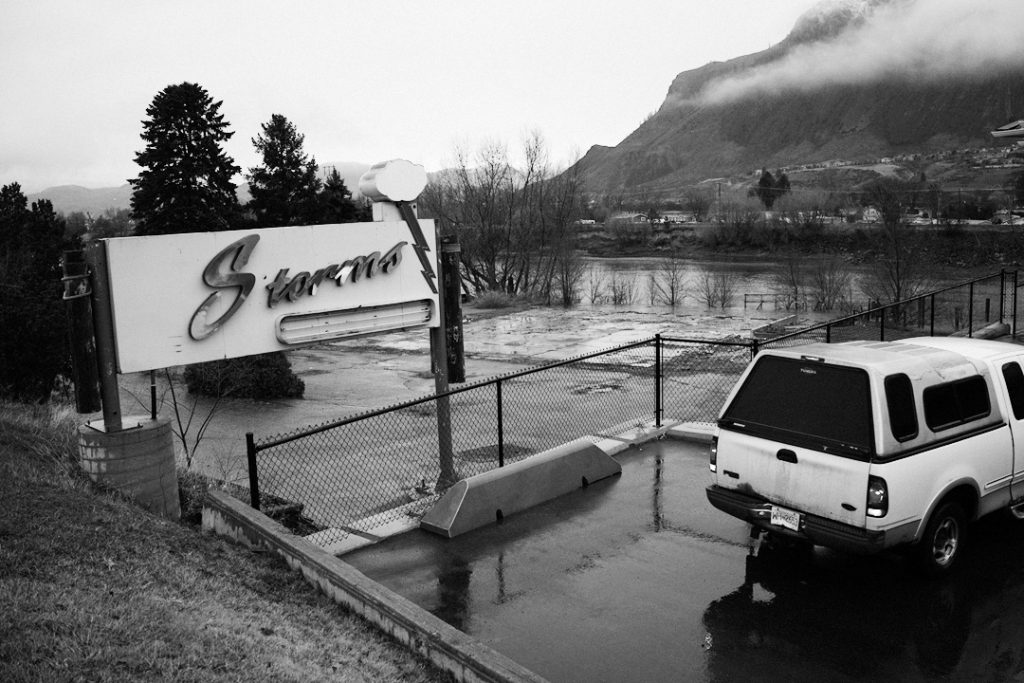 car in a parking lot next to a river and a derelict sign. Photo: Paul Urbanski
